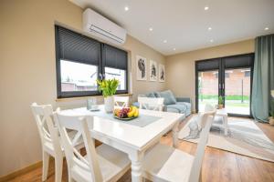 a dining room and living room with a white table and chairs at Sun & Garden House in Oświęcim