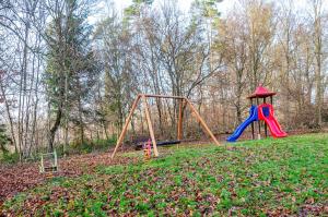 einen Spielplatz mit zwei Schaukeln und einer Rutsche in der Unterkunft Twistesee Ferienhaus 2 in Wetterburg