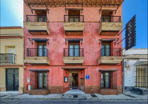 a red building with balconies on the side of it at Hotel Pozo Rey by Youroom in Chipiona