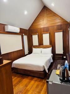 een slaapkamer met een bed in een kamer met houten lambrisering bij JJ Palace เจเจ พาเลซ in Ban Si Than