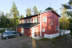 a red house with a car parked in front of it at Pyhäkoti D - 30 Meters From the Slopes in Pyhätunturi