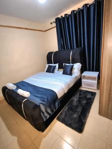 ein Bett mit einem schwarzen Kopfteil in einem Zimmer in der Unterkunft Smiley Stay in Nakuru