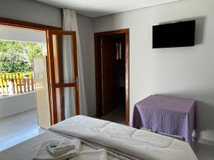 a bedroom with a bed and a table and a television at Pousada do Rui in Caparaó Velho