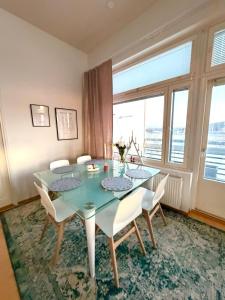 a dining room with a glass table and white chairs at Big river view city apartment in Rovaniemi +9 photos