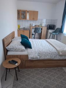 a bedroom with a bed with blue pillows and a table at Studio apartman KONAK in Kupres