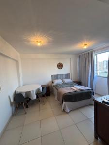 a bedroom with a bed and a table and a window at Apes Raizes Douradas in Campinas