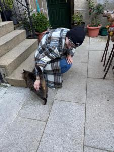 Ein Mann, der mit einem Fisch in der Hand in der Hocke sitzt in der Unterkunft Ático Pequeño Paraíso Combarro in Combarro