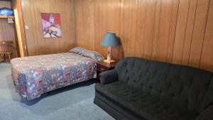 een slaapkamer met een bed, een bank en een lamp bij Black Cat Guest Ranch in Brule Mines