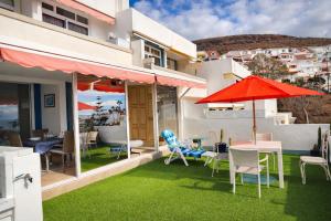 a patio with chairs and tables and an umbrella at Azahara Beach in Arona
