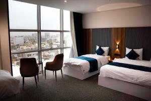 ein Hotelzimmer mit zwei Betten und einem großen Fenster in der Unterkunft Wlat Hotel in Erbil + 73 Fotos
