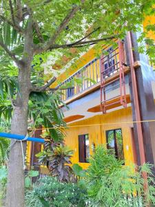 a yellow and white building with a balcony at Jenises Inn in El Nido