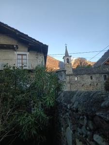 a stone wall next to a building with a clock tower at La Casa Antica in Pont-Saint-Martin