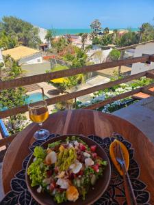 een bord salade op een tafel met een glas wijn bij Shanti Om Refúgio Pousada e Yoga in Cascavel