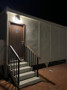 eine Treppe, die zu einer Tür mit Licht führt in der Unterkunft خيم مبيت ملكية بالصياهد in Rumāḩ