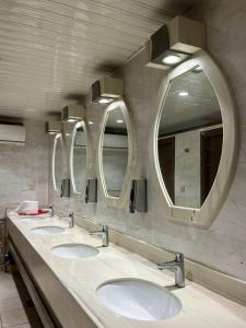 a bathroom with three sinks and three mirrors at خيم مبيت ملكية بالصياهد in Rumāḩ