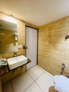 een badkamer met een wastafel en een spiegel bij Kasa Hotels in Gandhinagar