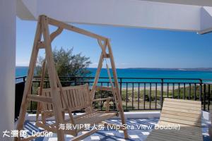 een schommel op een veranda met de oceaan op de achtergrond bij Kenting Dawan Homestay in Kenting