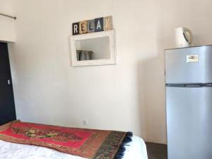 une chambre avec un réfrigérateur et une couverture sur un lit dans l'établissement El-Sangha Studio 2mina pieds de la plage de baie du cap, à Ruisseau Créole
