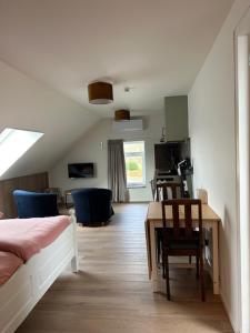 a bedroom with a bed and a desk and a kitchen at 't Veurhuus in Ansen