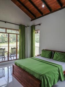 a bedroom with a bed with green sheets and windows at Forest & Fields Sinharaja - A Tale Of 2 Villas in Deniyaya