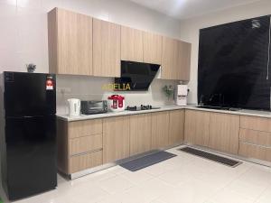 a kitchen with a black refrigerator and wooden cabinets at Adelia SweetHome in Kajang