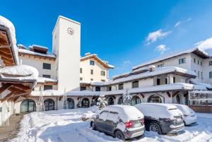 a building with snow covered cars parked in front of it at Hostdomus - Nube d'Argento in Sestriere +19 photos