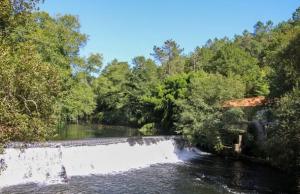 een rivier met een brug en wat bomen en water bij Refúgio do Ribeirinho in Paredes de Coura