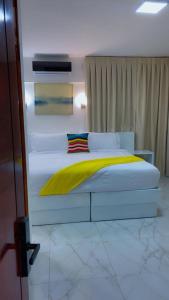 a bedroom with a white bed with a yellow blanket at Zile Hotel in Boca Chica