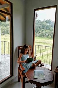 a little girl sitting on a table reading a book at Forest & Fields Sinharaja - A Tale Of 2 Villas in Deniyaya +85 photos
