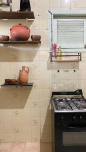 een keuken met een fornuis en planken met potten en pannen bij FLOR DE ARUANDA - Hostel e Acampamento in Cabo de Santo Agostinho