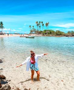 a woman standing on a beach with her arms outstretched at Encantos do Morro in Cayru