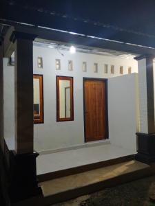 a white house with wooden doors and windows at Sherin Homestay in Pulau Sarang