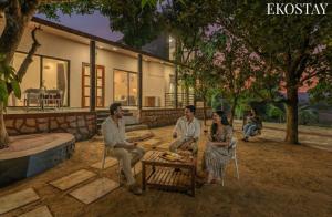 a group of people sitting outside of a house at EKOSTAY - Brick Wood in Karjat