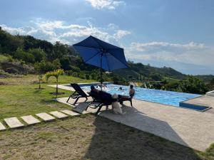 a person sitting on a bench under an umbrella next to a pool at Casa Vacacional in Loja