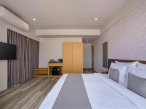 a hotel room with a bed and a television at Pride Elite Gandhinagar in Gandhinagar +19 photos