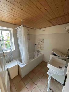 een grote badkamer met een bad en een wastafel bij Maison calme et agréable proche de la mer in Saint-Gervais