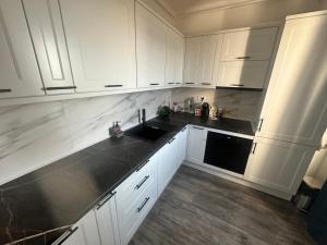 a kitchen with white cabinets and black counter tops at Garsoniera lux in Craiova
