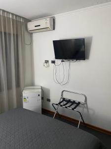 een slaapkamer met een bed en een flatscreen-tv bij Hotel Stella in Talca