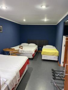 een kamer met 3 bedden en een flatscreen-tv bij Hotel Stella in Talca