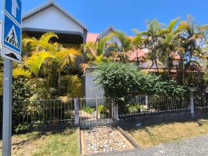 a fence in front of a house with palm trees at Location saisonnière Chez Paulette in Cilaos