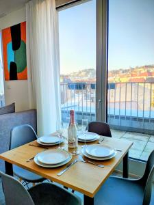a wooden table with plates and wine glasses and a window at MamaStay Andel Apartments in Prague