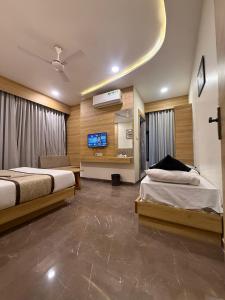a hotel room with two beds and a flat screen tv at Hotel Krish villa in Vadodara