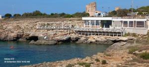 een gebouw op de rotsen naast een waterlichaam bij Vento sulle Onde - Casa Nunù in Torre Suda