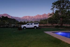 a white truck parked in a yard with mountains in the background at De Hoop Farm - Mountain View in Breërivier