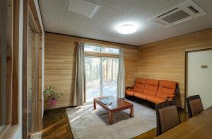 a living room with an orange couch and a table at Lake&Mountain Hamamatsu inn in Hamamatsu