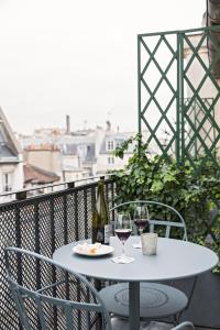 a table with two glasses of wine on a balcony at Hotel Paradis in Paris