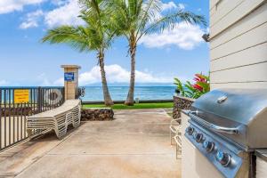 a patio with a grill and palm trees and the ocean at Kahana Reef 111 · KR 111 Renovated OceanFront Condo Romantic Get in Kahana