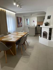 a dining room and kitchen with a wooden table and chairs at Sóstó Liget House in Igricetanya
