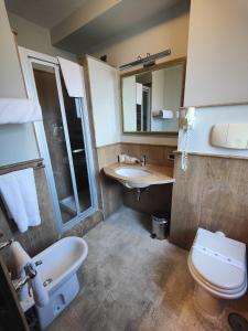 een badkamer met een wastafel, een toilet en een spiegel bij Hotel Lemi in Benevento