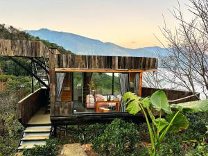 une petite maison sur une colline avec des montagnes en arrière-plan dans l'établissement Cloud Garden, à Bắc Yên